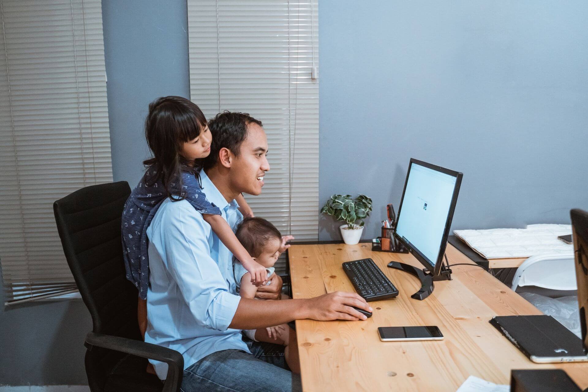 A father and two children sitting in front of a computer