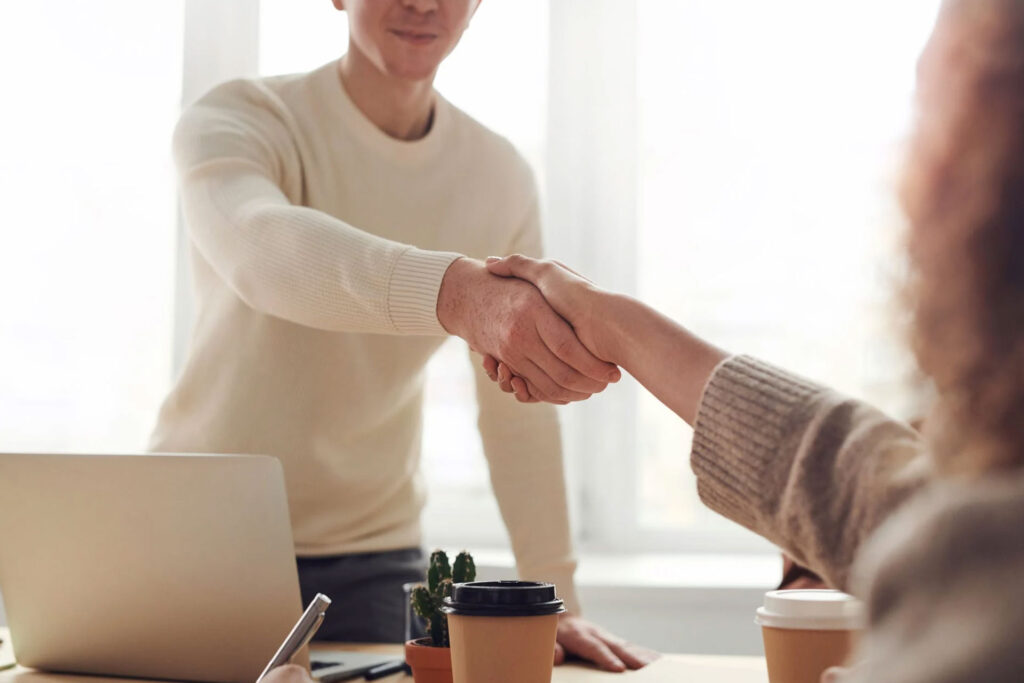 An applicant who has just been hired, shaking hands with his interviewer
