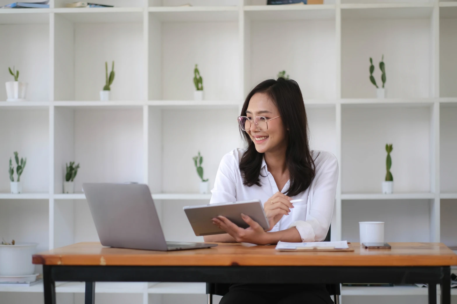 A young woman exploring a digital marketing career path, holding a tablet and reviewing content on a laptop