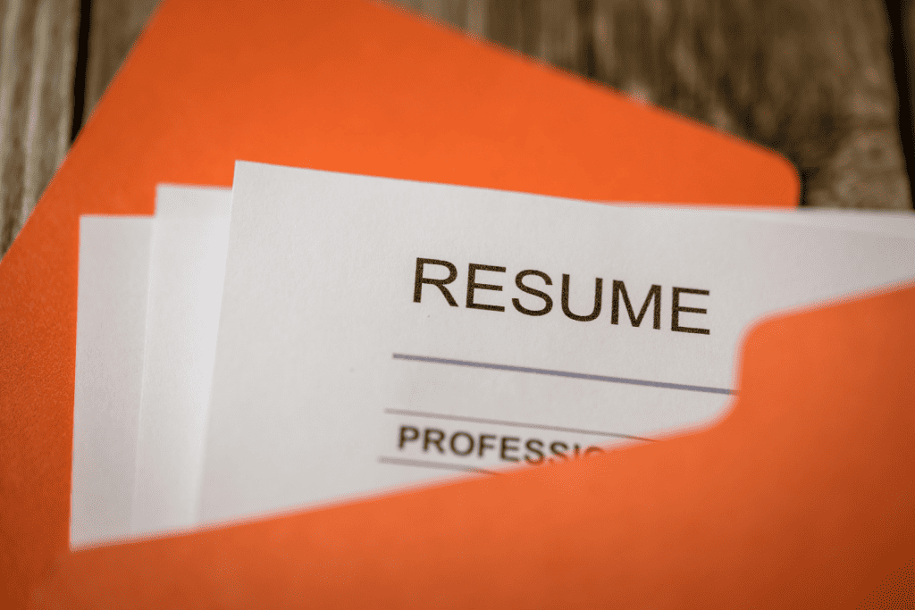  A resume inside an orange folder on top of a wooden desk 