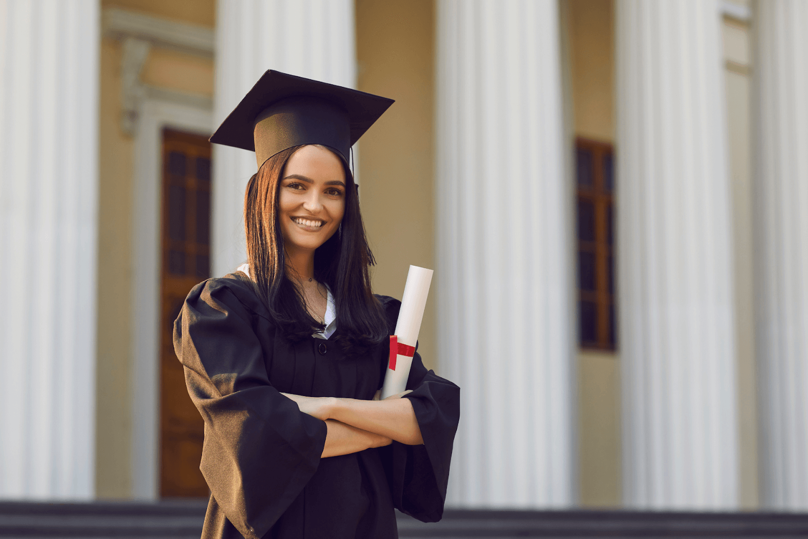 A smiling young woman in a graduation cap and gown with her diploma