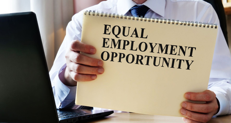 A man holds a notebook with the words “equal employment opportunity” on the cover