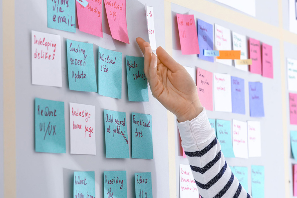 A person arranging task notes on a to-do list board 