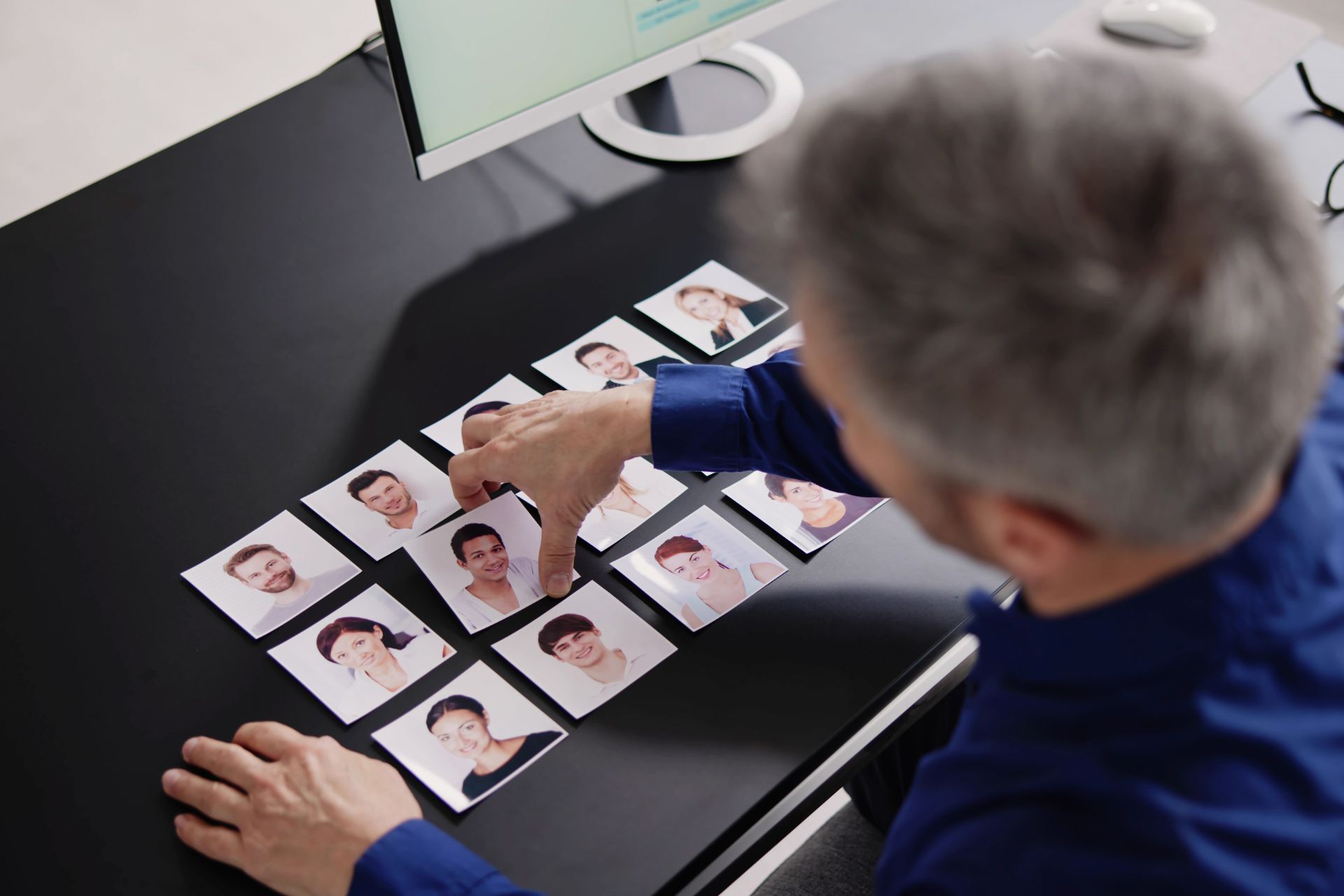 A recruiter picking up a photo of a man from a collection