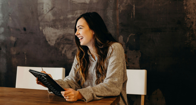 A woman smiling as she holds a tablet using technology in recruitment and selection