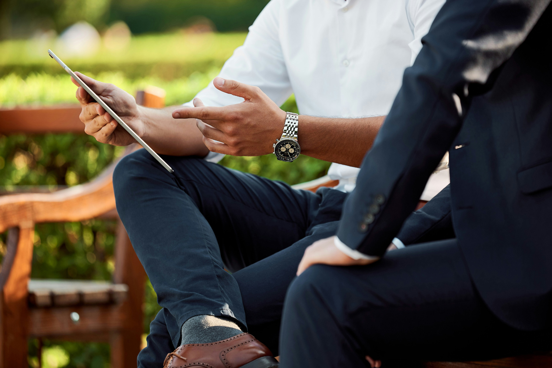 Two people discussing something on a tablet in a park