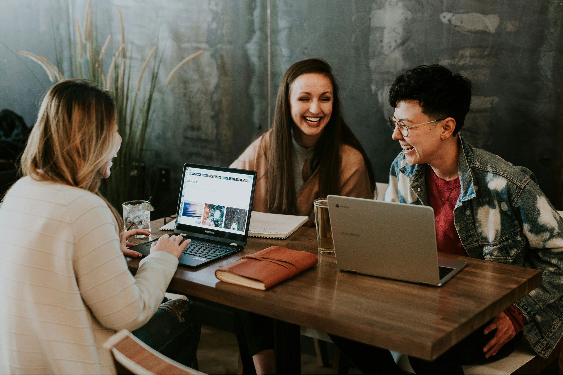 Three employees sitting at a workstation and laughing