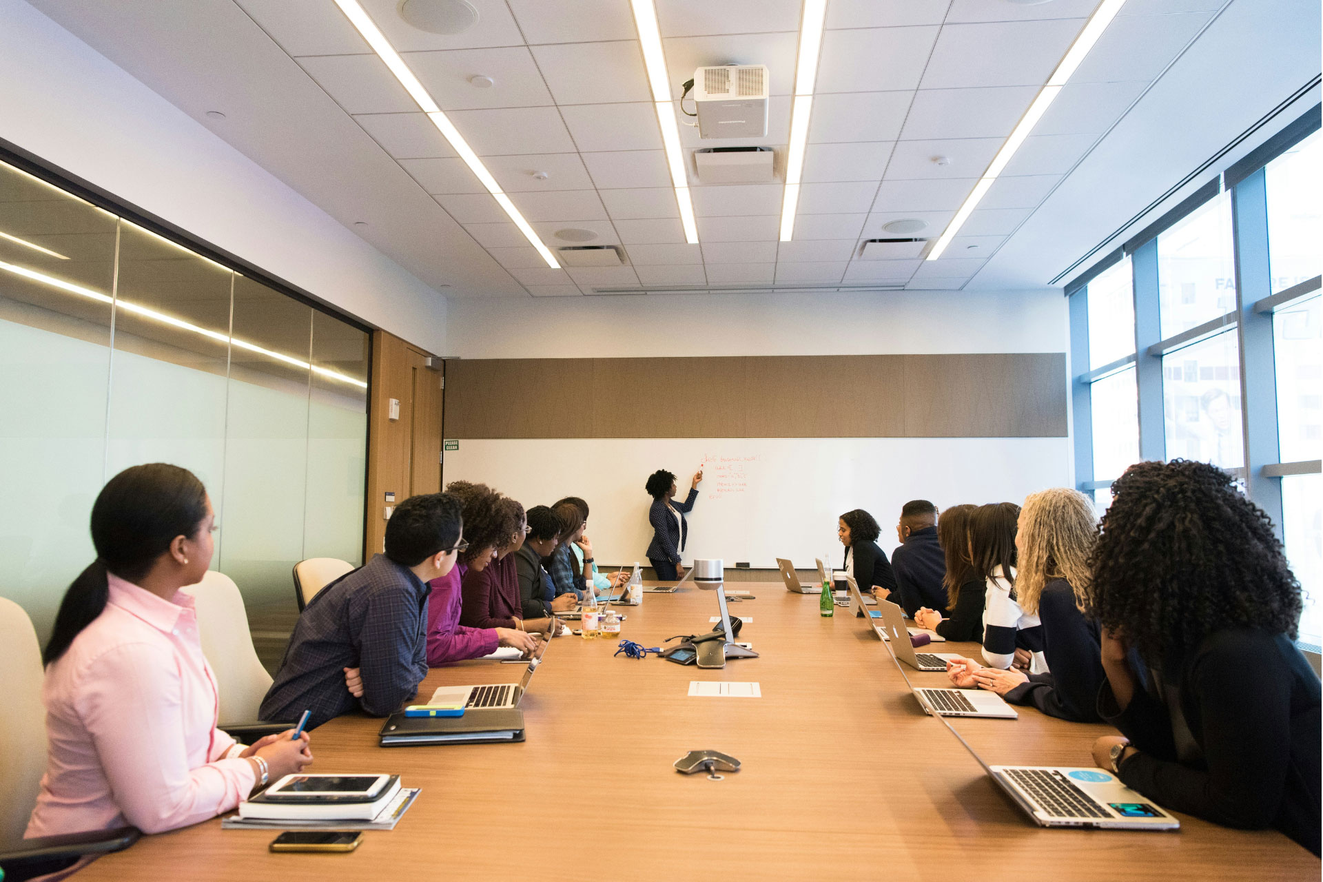 A group of people listening to a woman in a conference room