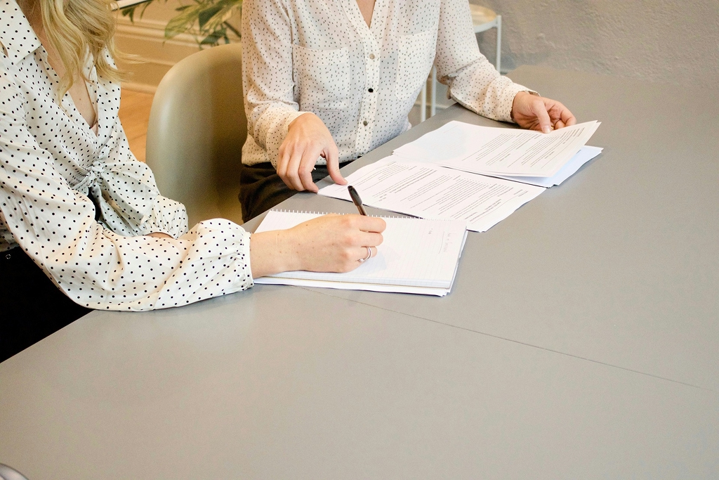 Two women discussing a digital marketing specialist resume and taking notes