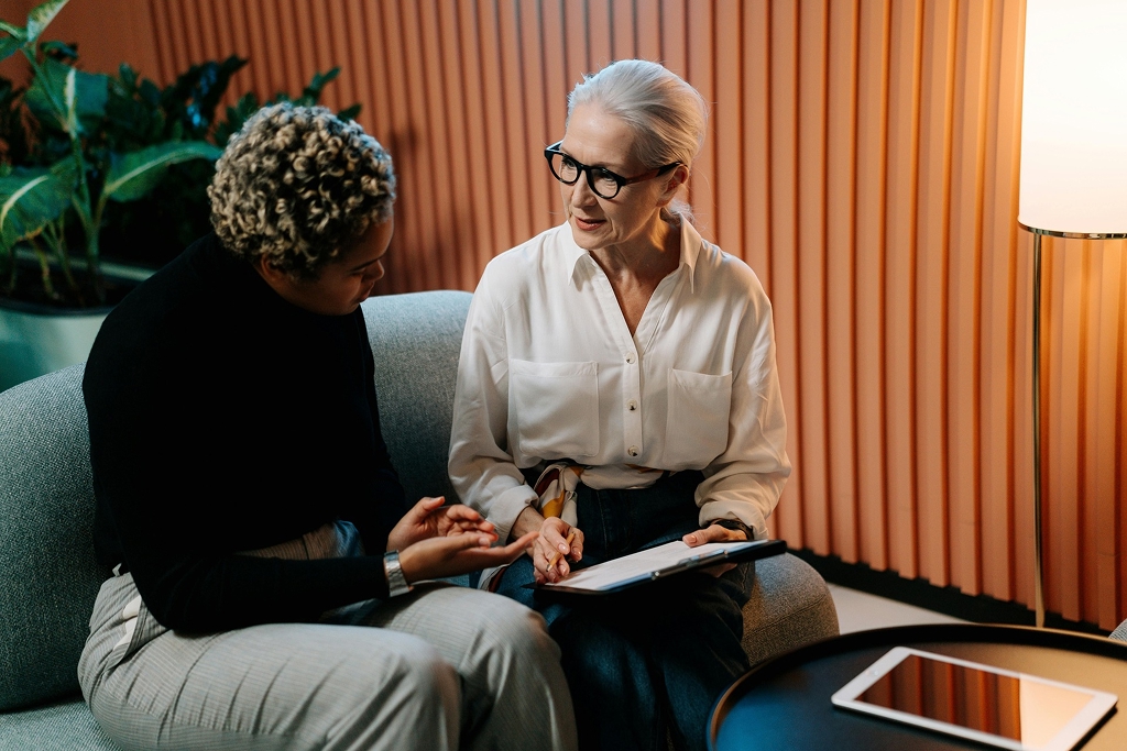 Two women discussing a digital marketing resume on a couch 