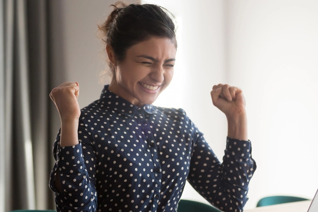 A woman cheers at her desk