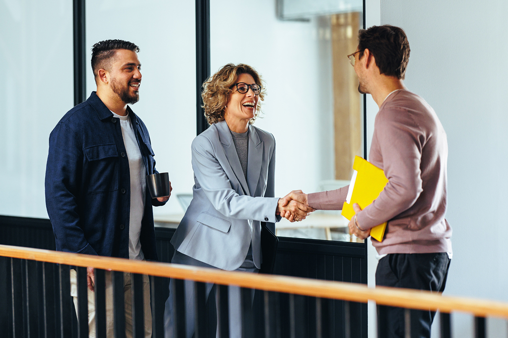 Boss shaking hands with a new employee in an office.