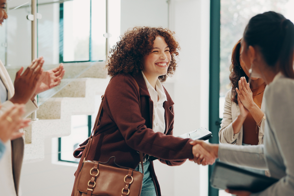 New employee happily shaking hands with colleagues