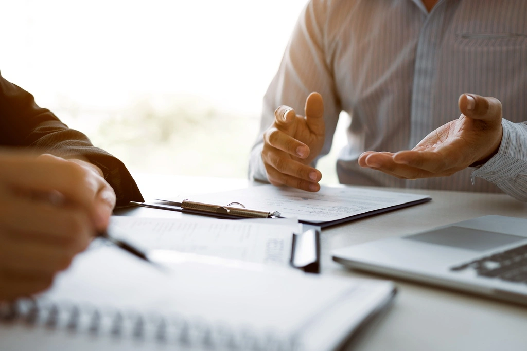 Two individuals make notes during a meeting