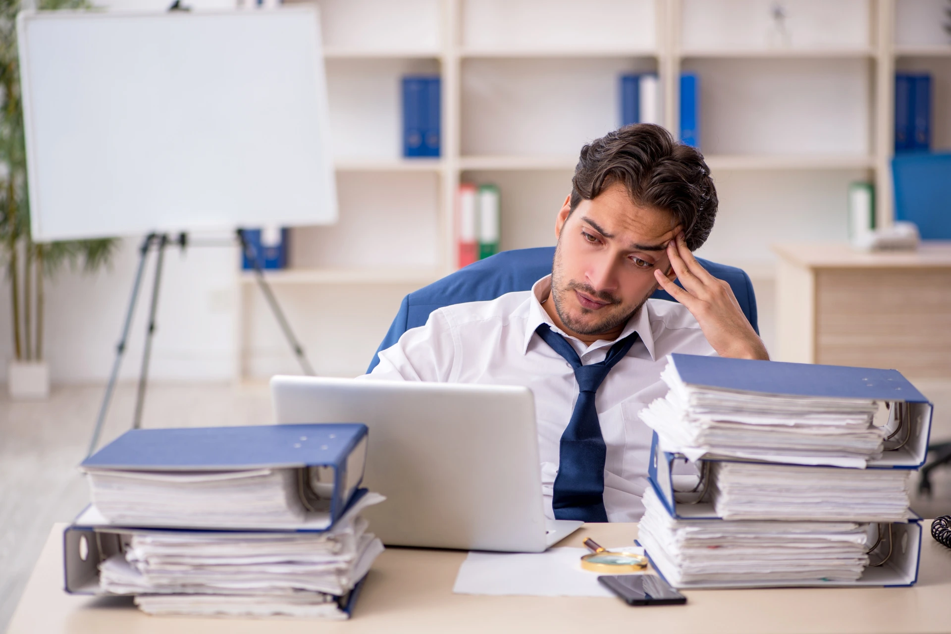 Male employee overwhelmed by paperwork
