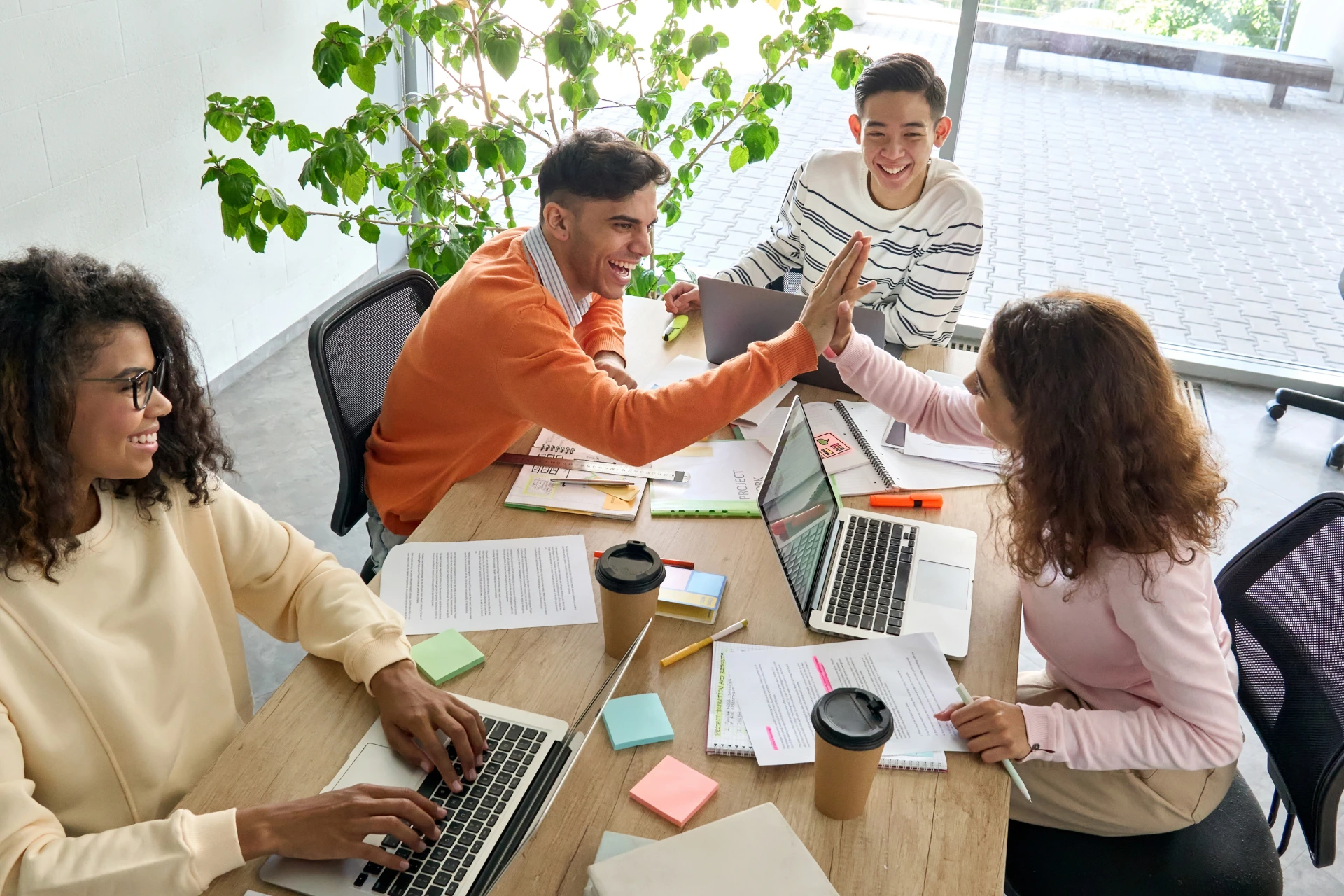  A group of four Gen Z creatives happily working together in an office