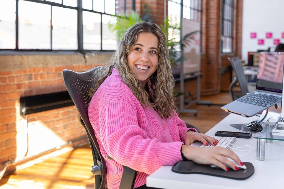  Blonde girl in a pink sweater on her computer