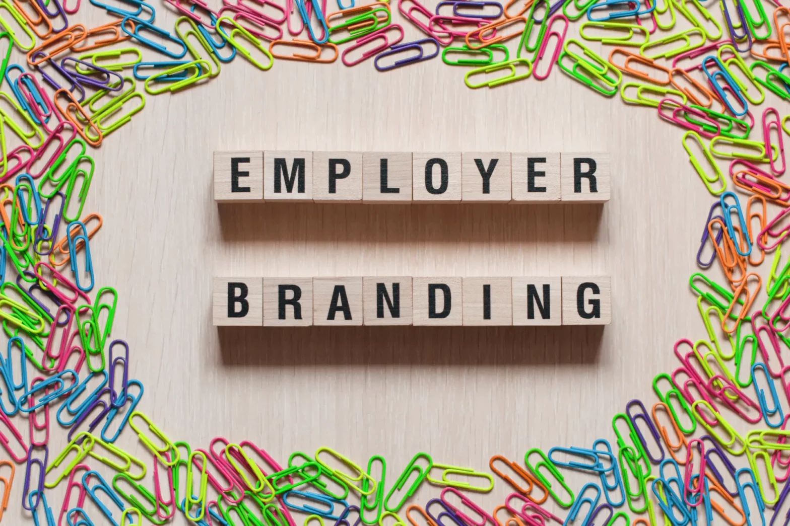 Wood blocks spell the term “Employer Branding” surrounded by paper clips