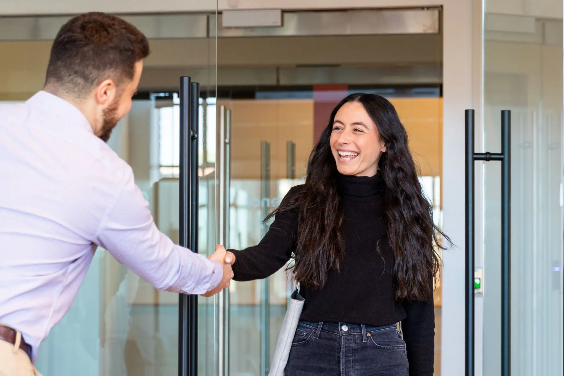 A man in a blue shirt shaking the hands of a woman in a black shirt