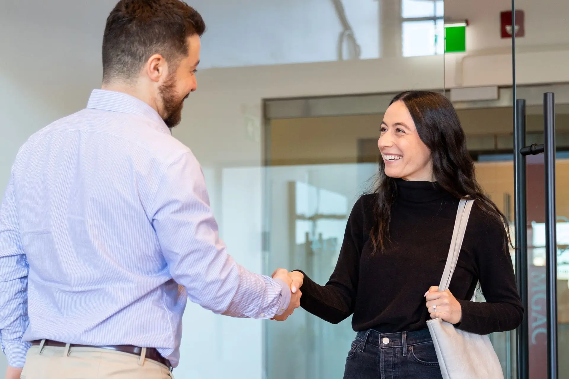 A man in a blue shirt shaking hands with a woman in a black shirt