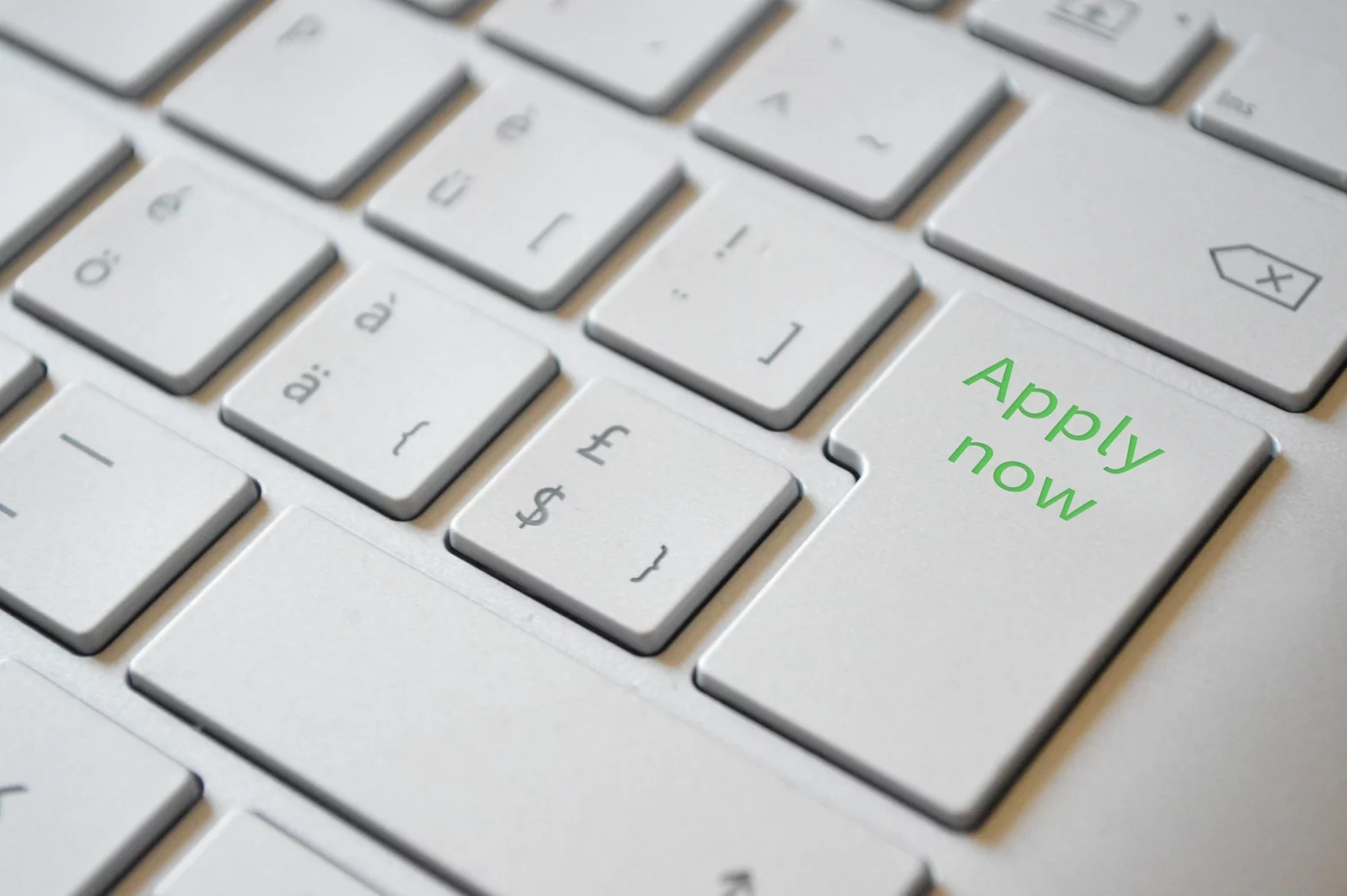 White keyboard with green text saying Apply Now!