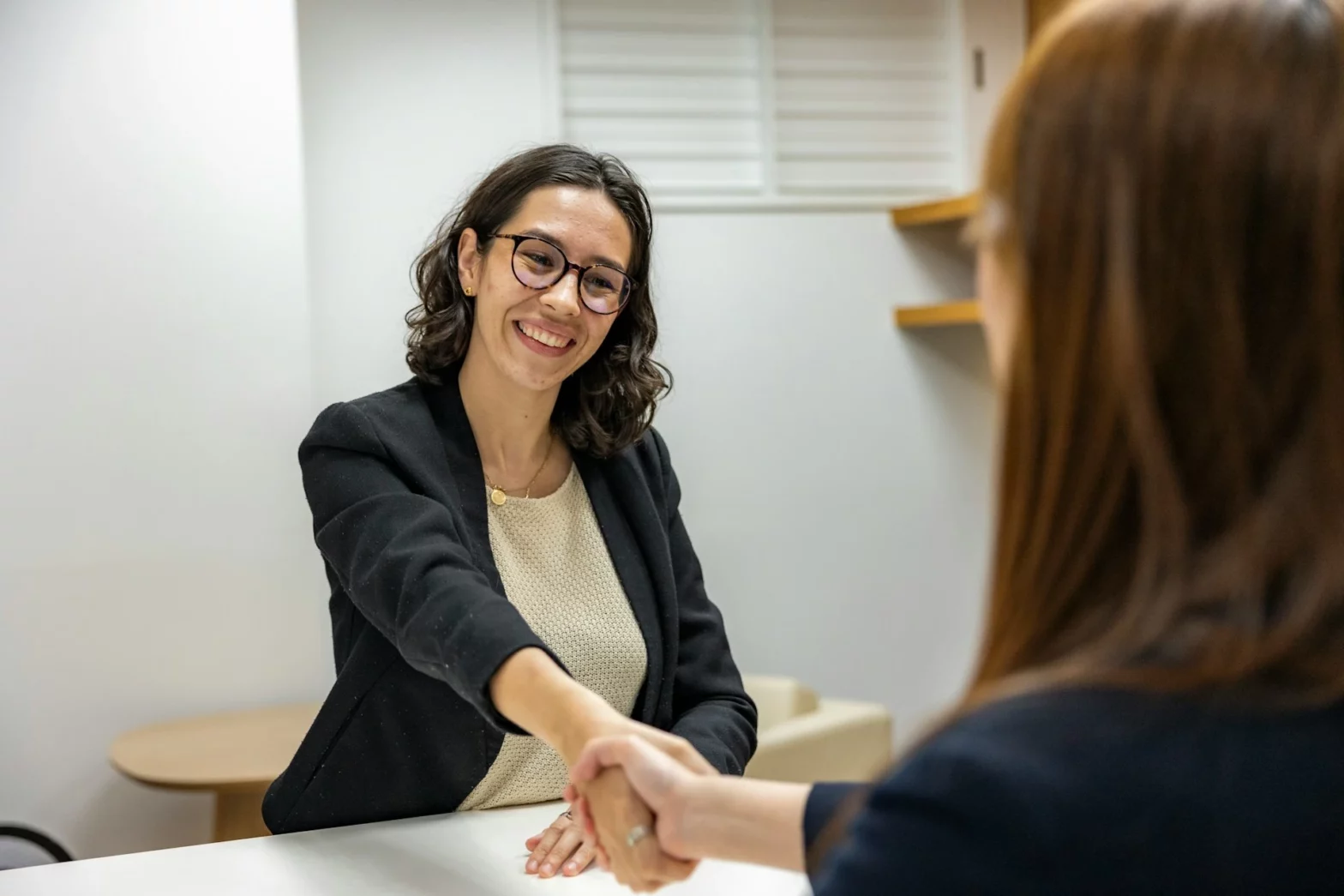 A female candidate in a black blazer shaking hands with HR