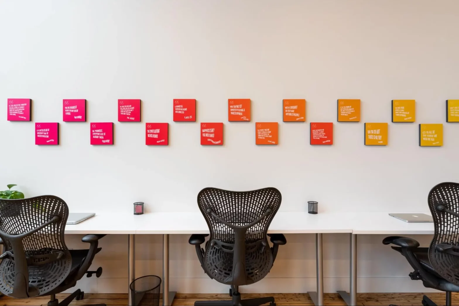 Three office chairs facing a white wall with motivational quotes on it