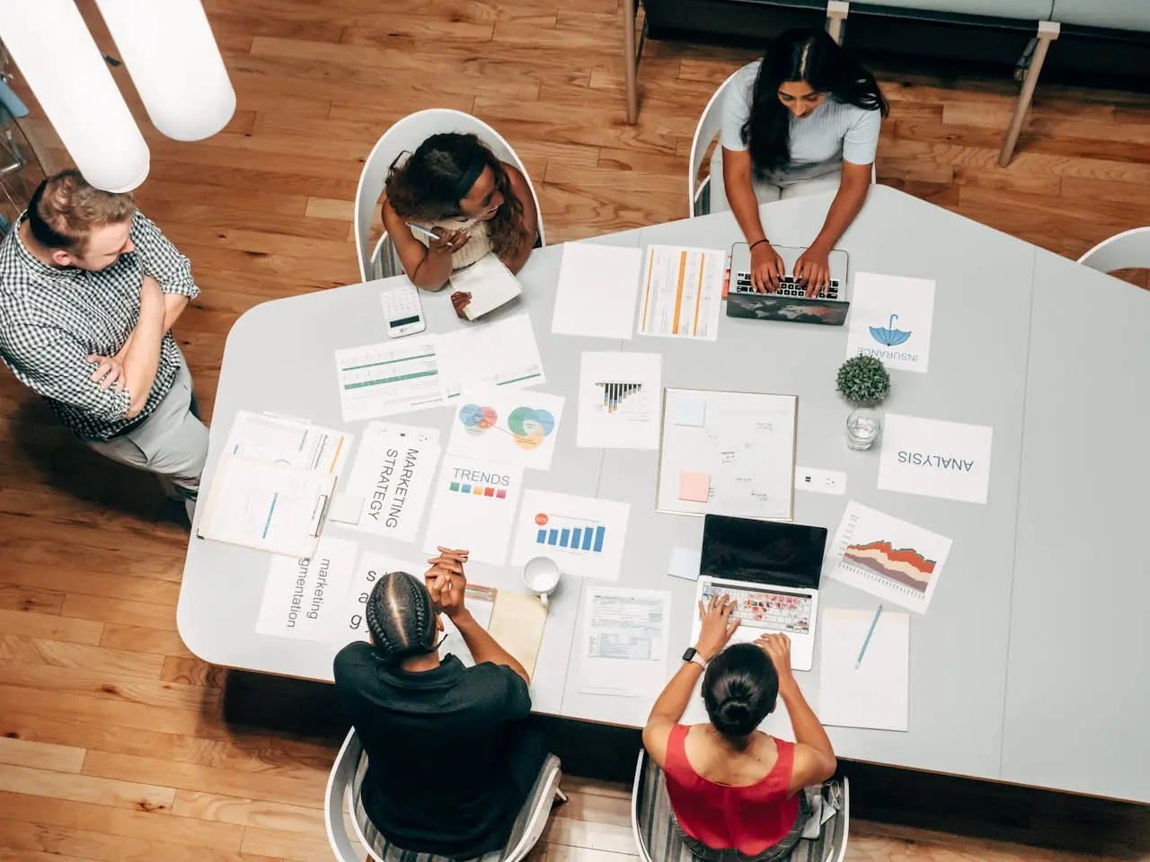 Four digital marketing professionals reviewing charts and campaign data on a large table