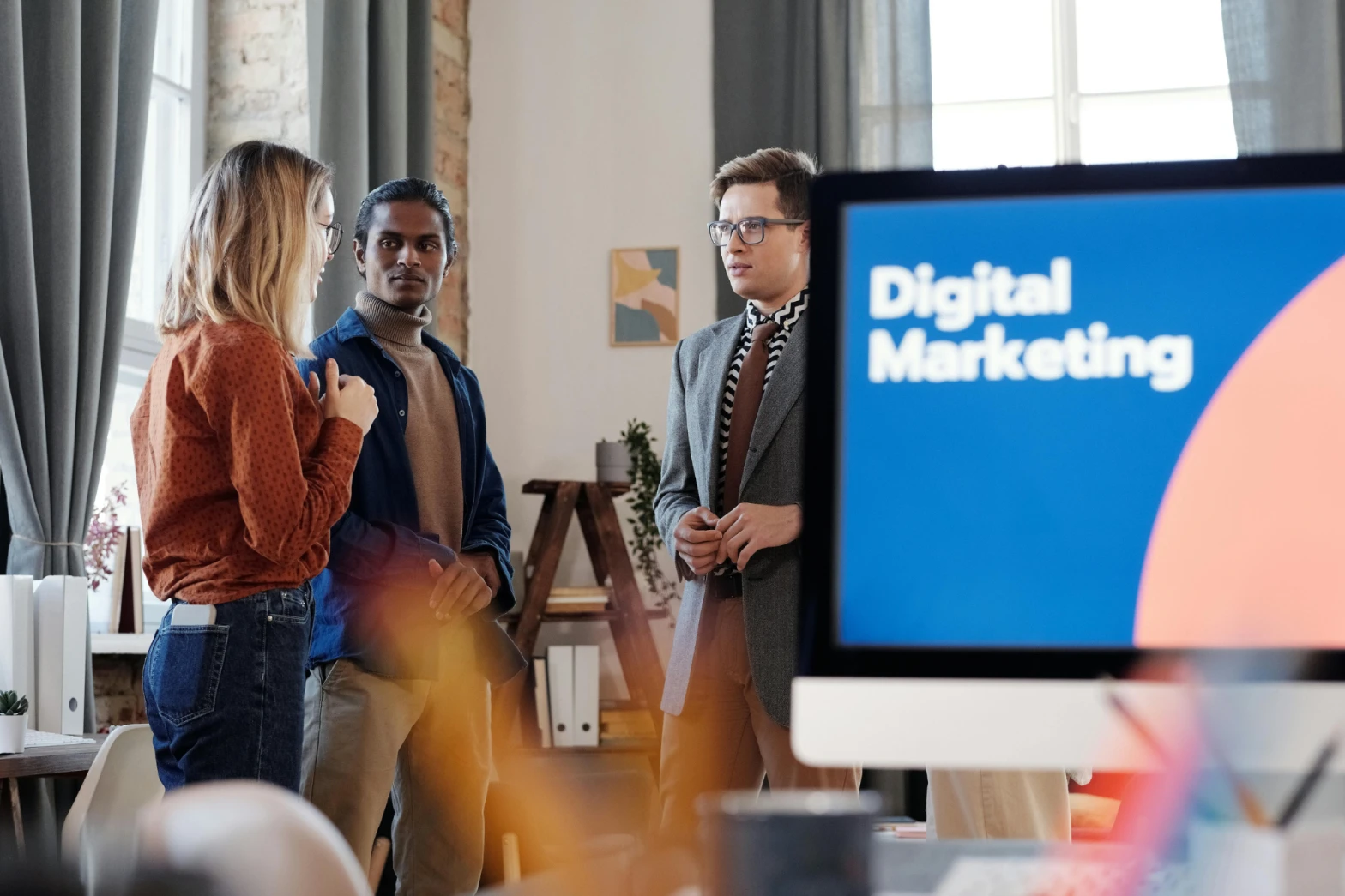 Group of marketers discussing digital marketing strategies in an office setting.