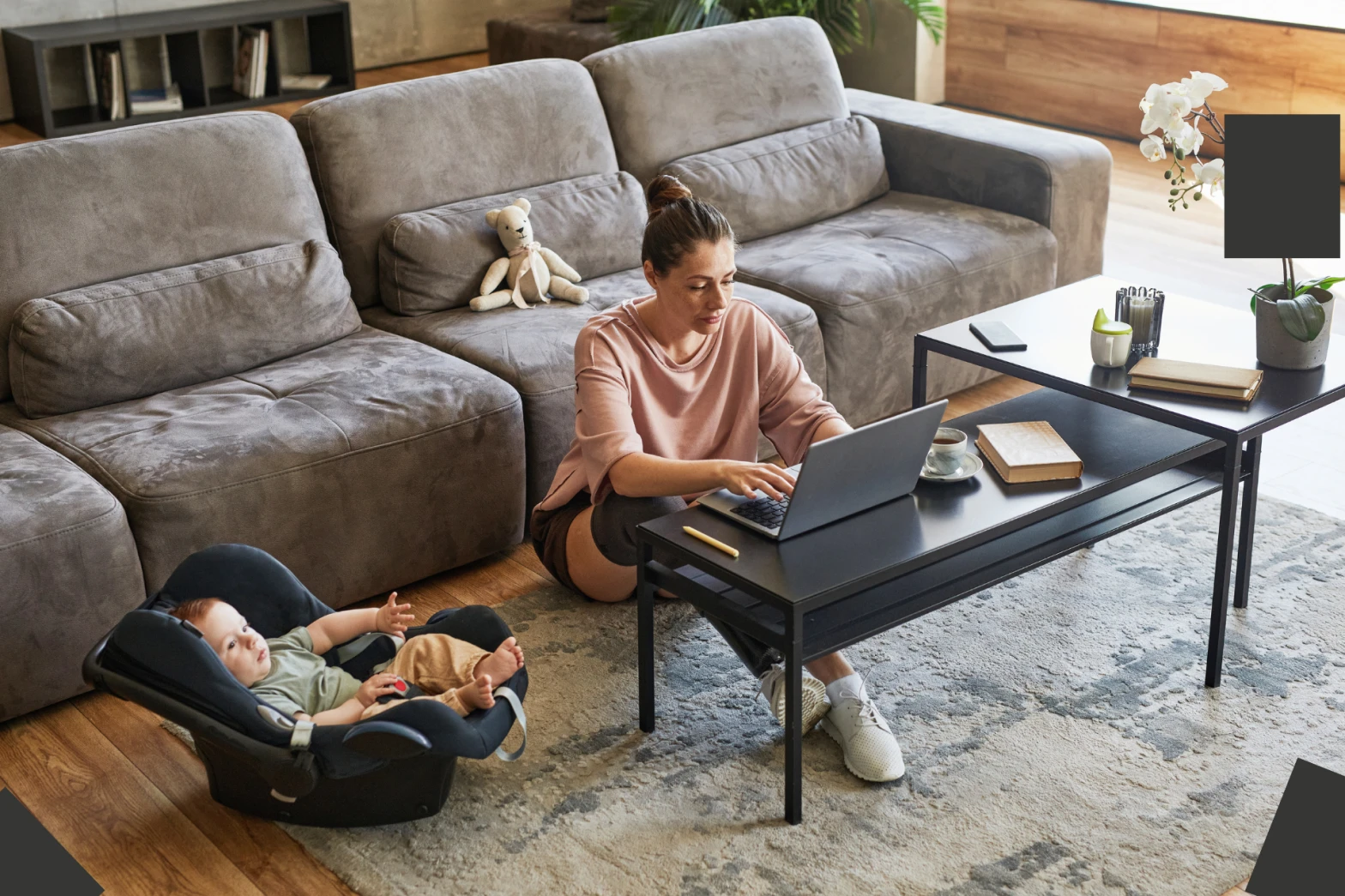 A mom working from home with her child lying in a carrier next to her