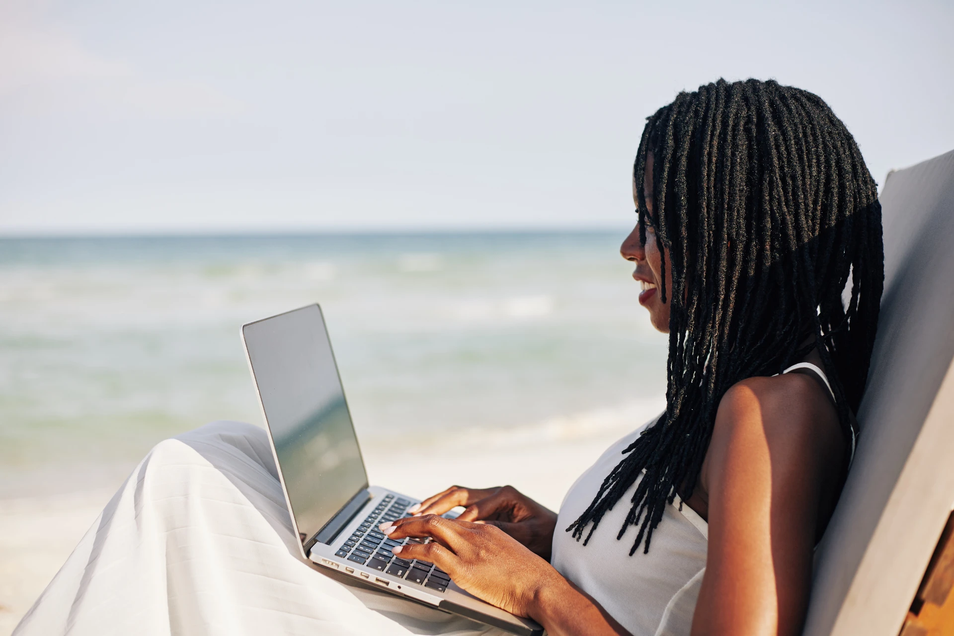 A digital nomad working on her laptop while at the beach