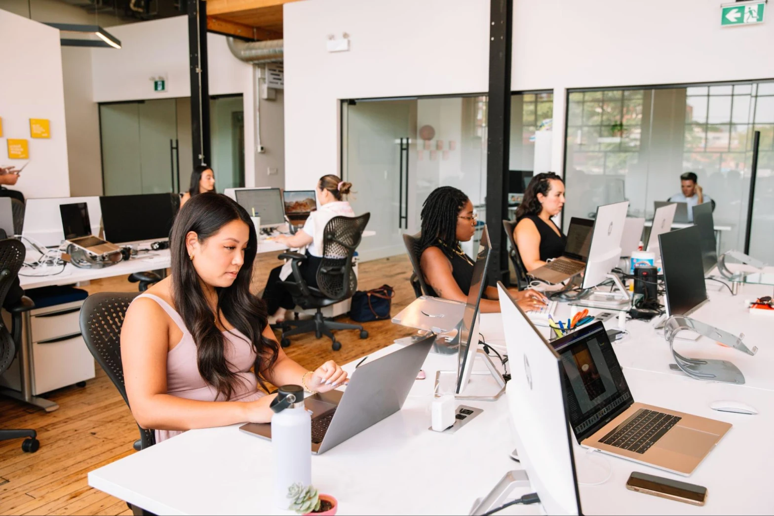 Employees in a brightly lit office all intently focused on their computers